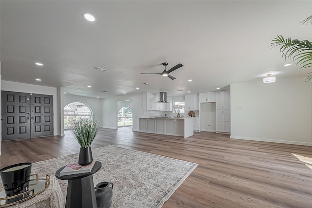 living area featuring recessed lighting, visible vents, light wood-style floors, a ceiling fan, and baseboards