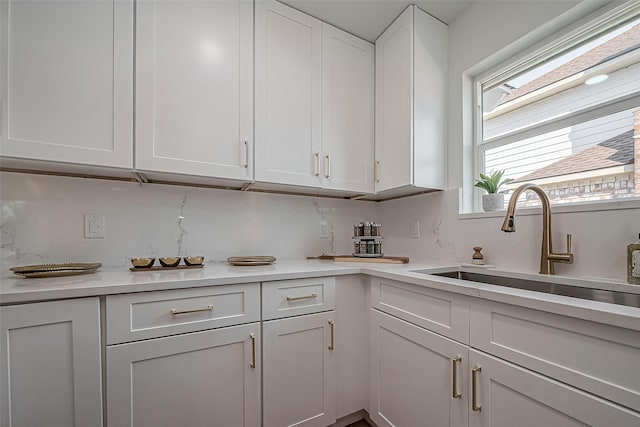 kitchen featuring light countertops, white cabinets, and a sink