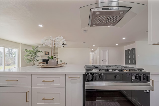 kitchen featuring stainless steel gas range, visible vents, and white cabinetry