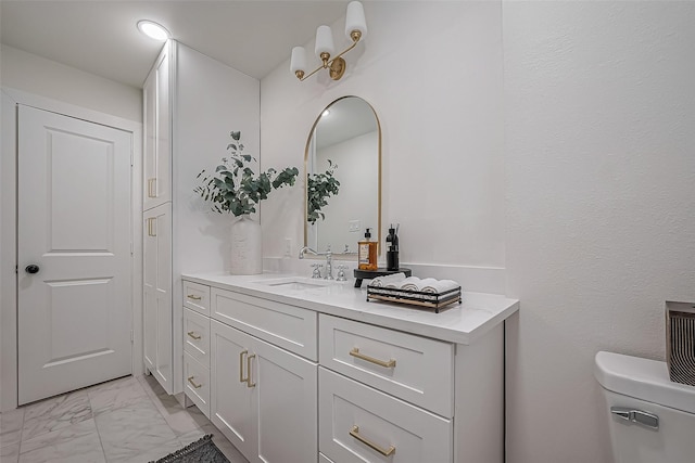 bathroom with marble finish floor, vanity, and toilet