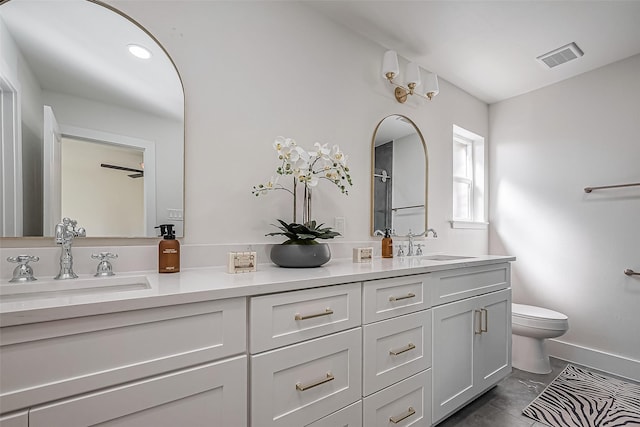 bathroom featuring toilet, double vanity, visible vents, and a sink