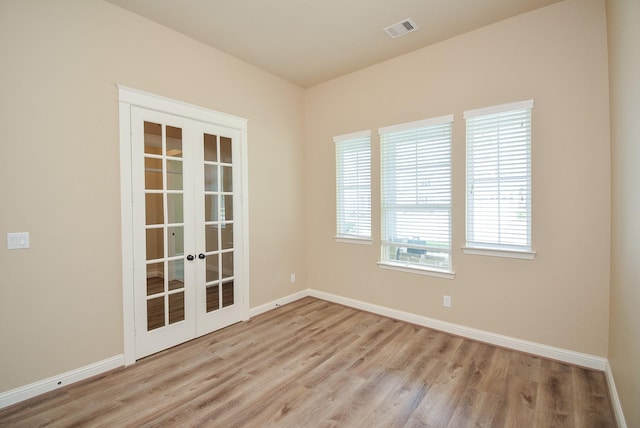 empty room with baseboards, visible vents, wood finished floors, and french doors