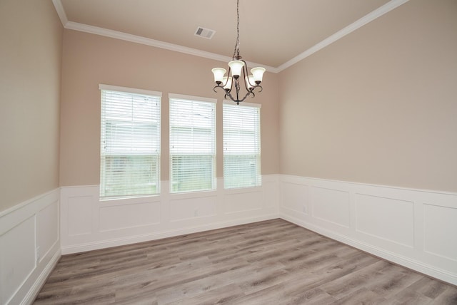 spare room with light wood finished floors, visible vents, a wainscoted wall, an inviting chandelier, and crown molding