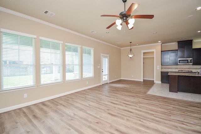 kitchen featuring plenty of natural light, visible vents, decorative backsplash, stainless steel microwave, and crown molding