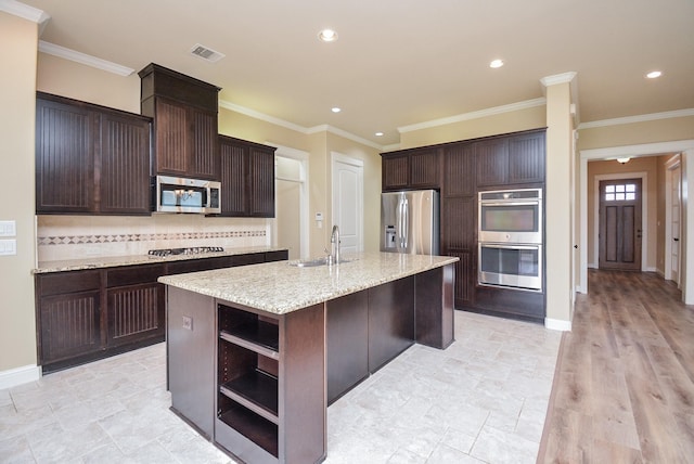 kitchen featuring open shelves, stainless steel appliances, visible vents, a sink, and an island with sink