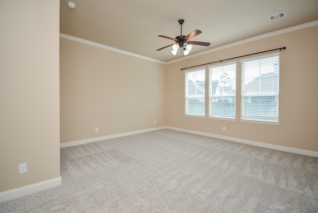 carpeted spare room featuring a ceiling fan, baseboards, visible vents, and crown molding