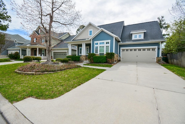 craftsman inspired home with a shingled roof, concrete driveway, a front yard, fence, and a garage