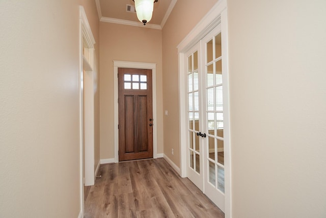 doorway to outside featuring baseboards, visible vents, ornamental molding, french doors, and light wood-type flooring