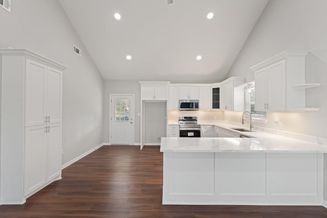 kitchen with stainless steel appliances, a peninsula, a sink, white cabinets, and open shelves