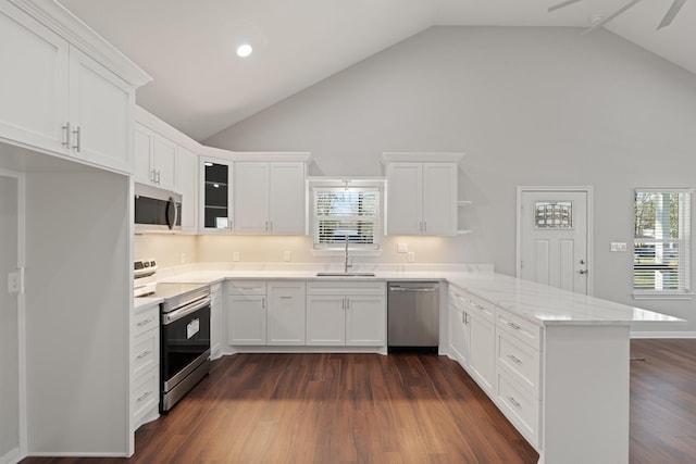 kitchen with a peninsula, dark wood-type flooring, a sink, white cabinetry, and appliances with stainless steel finishes