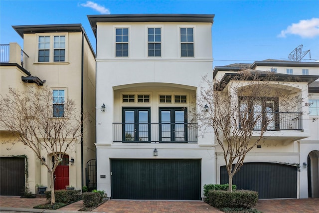 view of front of home featuring decorative driveway, an attached garage, and stucco siding