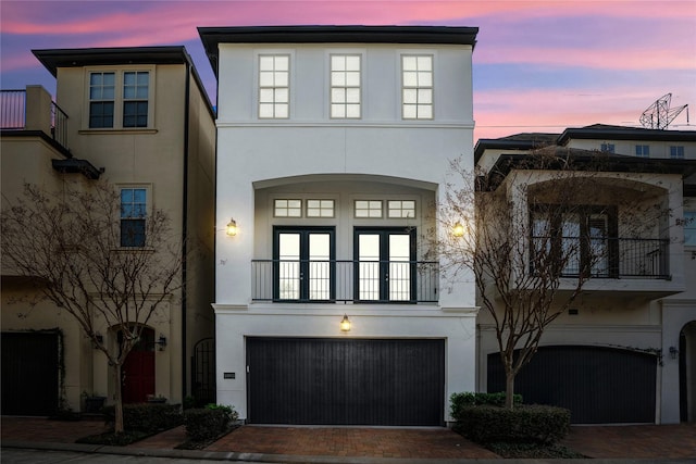 view of front of house with decorative driveway, an attached garage, and stucco siding