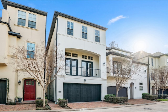 view of front of home with a garage, a balcony, decorative driveway, and stucco siding