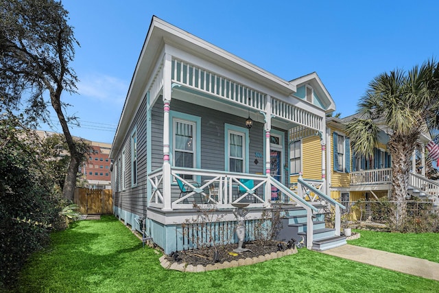 view of front facade featuring a porch, fence, and a front lawn