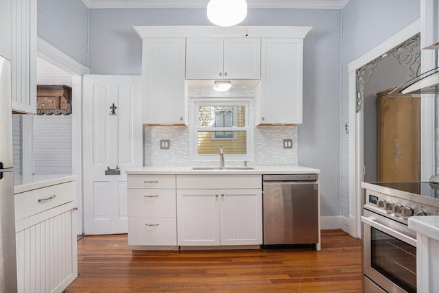 kitchen with wood finished floors, a sink, light countertops, appliances with stainless steel finishes, and crown molding