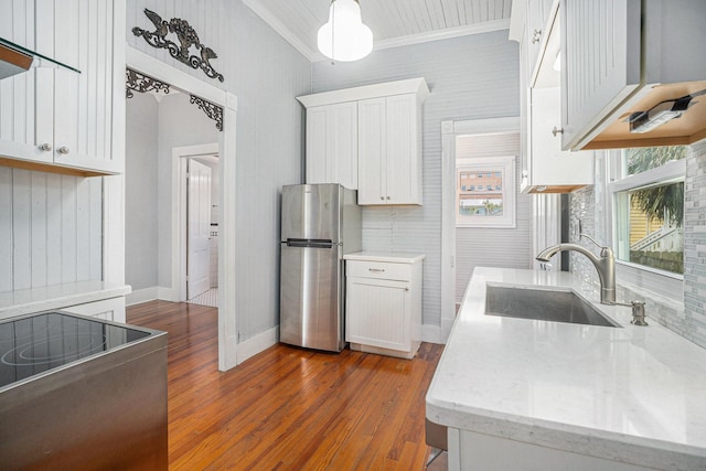 kitchen with dark wood-style floors, crown molding, freestanding refrigerator, white cabinetry, and a sink