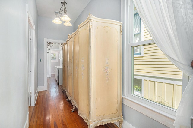 hallway featuring hardwood / wood-style flooring, baseboards, and an inviting chandelier