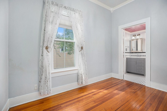 unfurnished room with wood-type flooring, crown molding, and baseboards