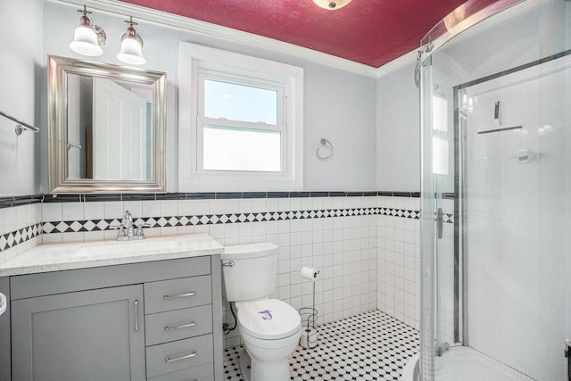 full bathroom featuring a stall shower, toilet, ornamental molding, vanity, and tile walls