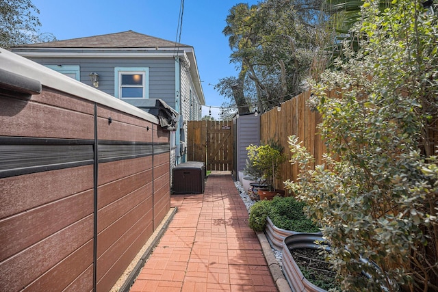 view of side of property featuring a patio area, a shingled roof, fence, and cooling unit