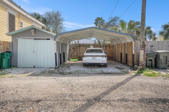 view of vehicle parking with a detached carport, fence, and driveway