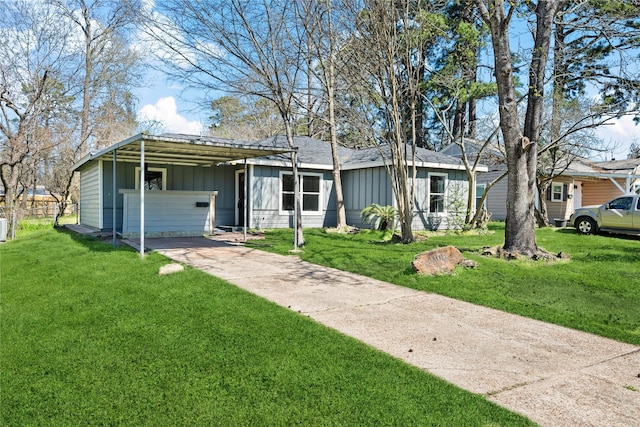 view of front of home with concrete driveway, a carport, board and batten siding, and a front lawn