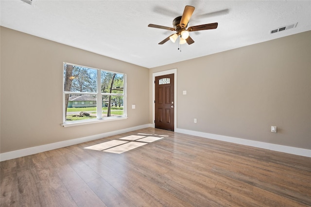 spare room with wood finished floors, visible vents, baseboards, ceiling fan, and a textured ceiling