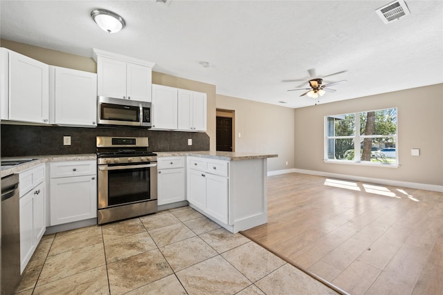 kitchen with visible vents, backsplash, open floor plan, a peninsula, and stainless steel appliances