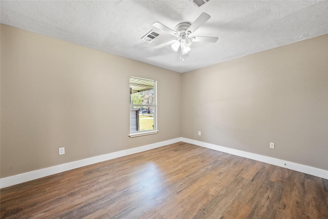 spare room featuring visible vents, a ceiling fan, baseboards, and wood finished floors