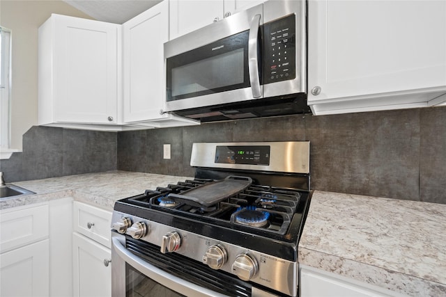 kitchen featuring decorative backsplash, light countertops, white cabinets, and stainless steel appliances