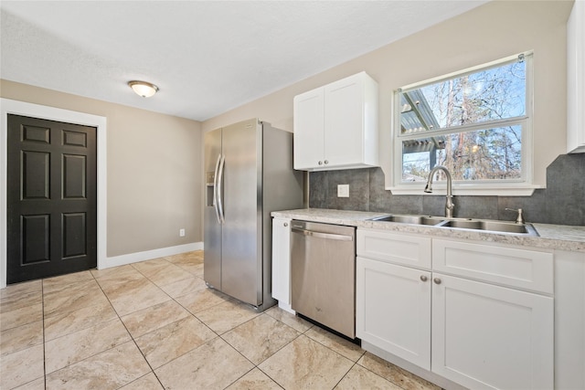 kitchen with a sink, stainless steel appliances, white cabinets, light countertops, and decorative backsplash