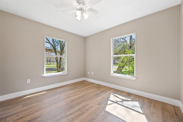 unfurnished room with baseboards, plenty of natural light, and wood finished floors