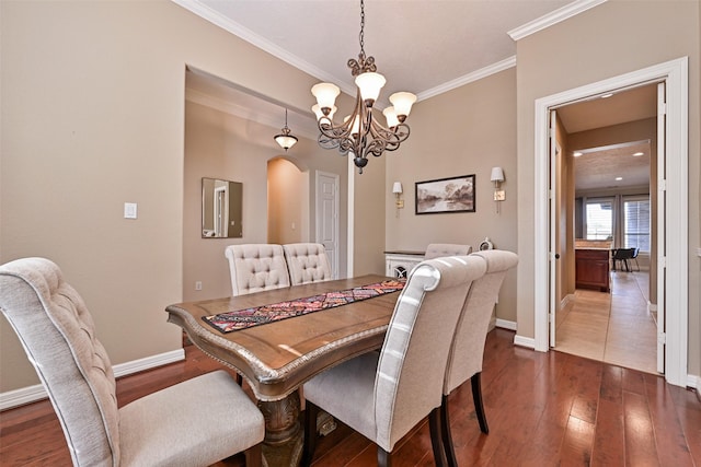 dining room featuring baseboards, ornamental molding, arched walkways, and dark wood-type flooring