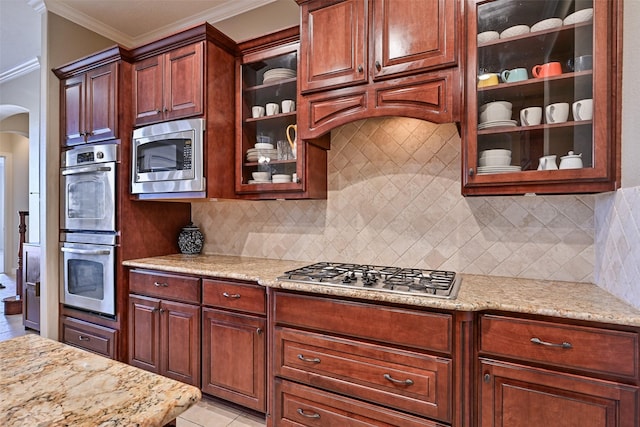 kitchen featuring arched walkways, crown molding, stainless steel appliances, light tile patterned flooring, and light stone countertops