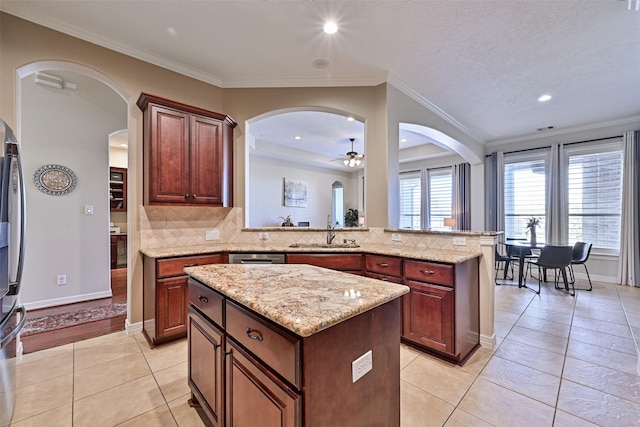 kitchen with light tile patterned floors, tasteful backsplash, a kitchen island, crown molding, and a sink