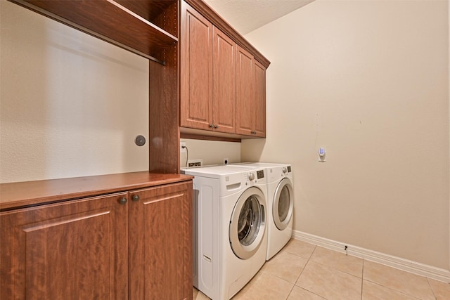 washroom with cabinet space, independent washer and dryer, baseboards, and light tile patterned floors