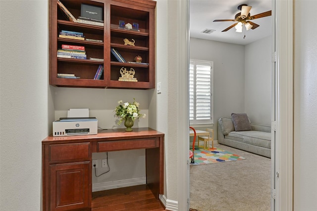 office with baseboards, visible vents, a ceiling fan, built in study area, and dark wood-style floors