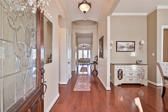 foyer with arched walkways, ornamental molding, dark wood-style floors, and baseboards