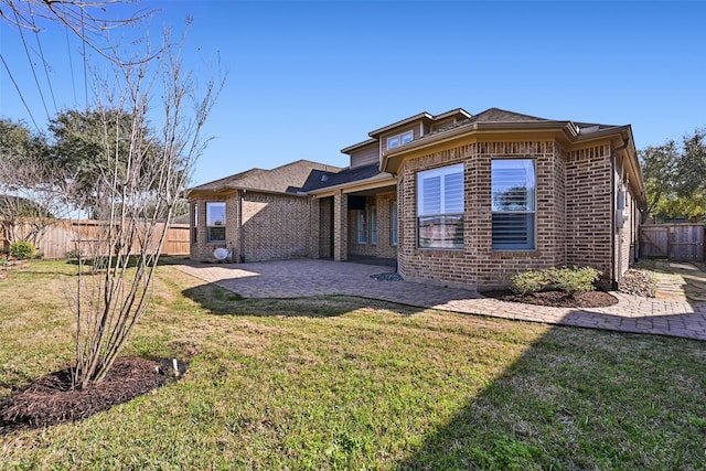 back of property featuring a yard, brick siding, a patio area, and a fenced backyard