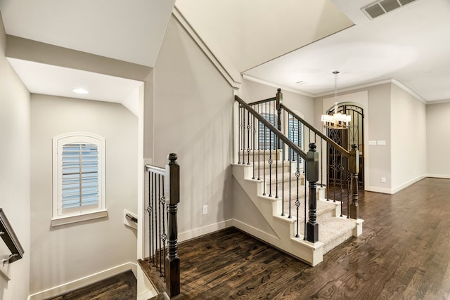 stairway with an inviting chandelier, baseboards, visible vents, and wood finished floors