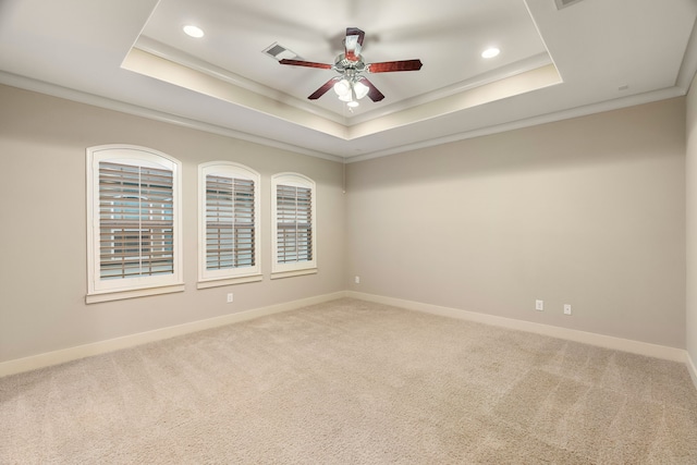 carpeted empty room featuring baseboards, visible vents, a raised ceiling, ceiling fan, and crown molding