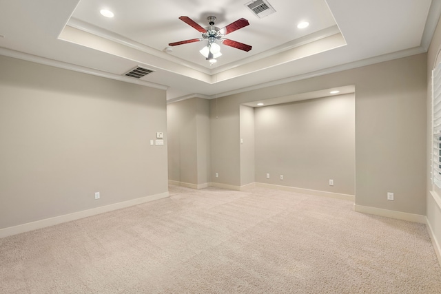 empty room featuring a tray ceiling, visible vents, and light colored carpet