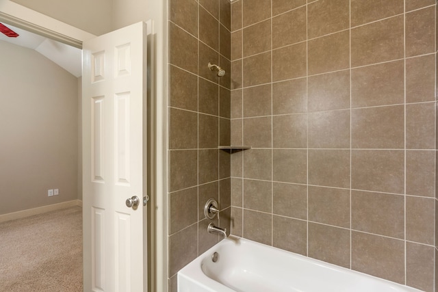 bathroom with lofted ceiling, washtub / shower combination, and baseboards