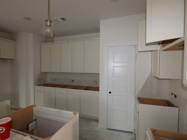 8622 Pier Cove Dr, Cypress, TX 77433 - kitchen featuring white cabinetry, hanging light fixtures, and concrete flooring