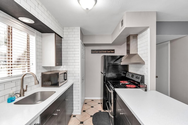 kitchen featuring stainless steel appliances, a sink, light countertops, wall chimney range hood, and tasteful backsplash