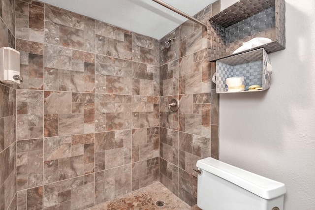 bathroom with a tile shower and toilet