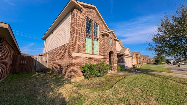 view of home's exterior featuring a garage, brick siding, a lawn, and fence