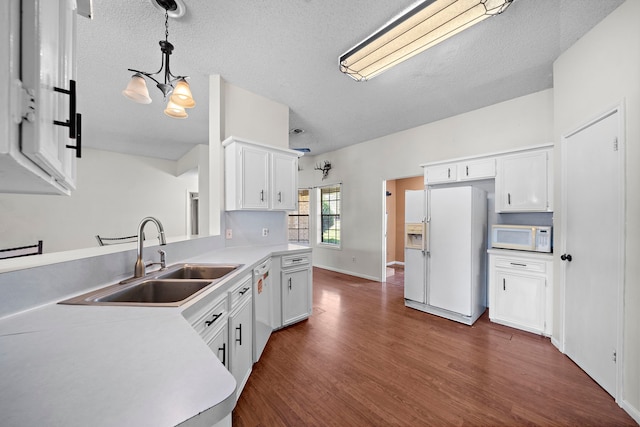 kitchen featuring white appliances, dark wood finished floors, light countertops, and a sink