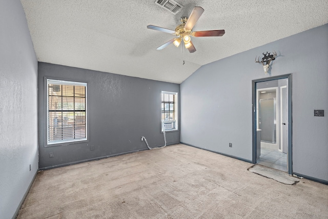 unfurnished room featuring lofted ceiling, visible vents, a textured wall, a ceiling fan, and carpet flooring