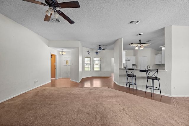 unfurnished living room with carpet, visible vents, a textured ceiling, and ceiling fan with notable chandelier